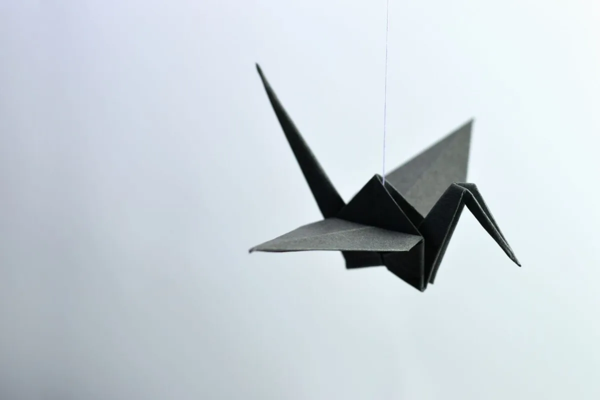 Żuraw origami złożony z ciemnego papieru