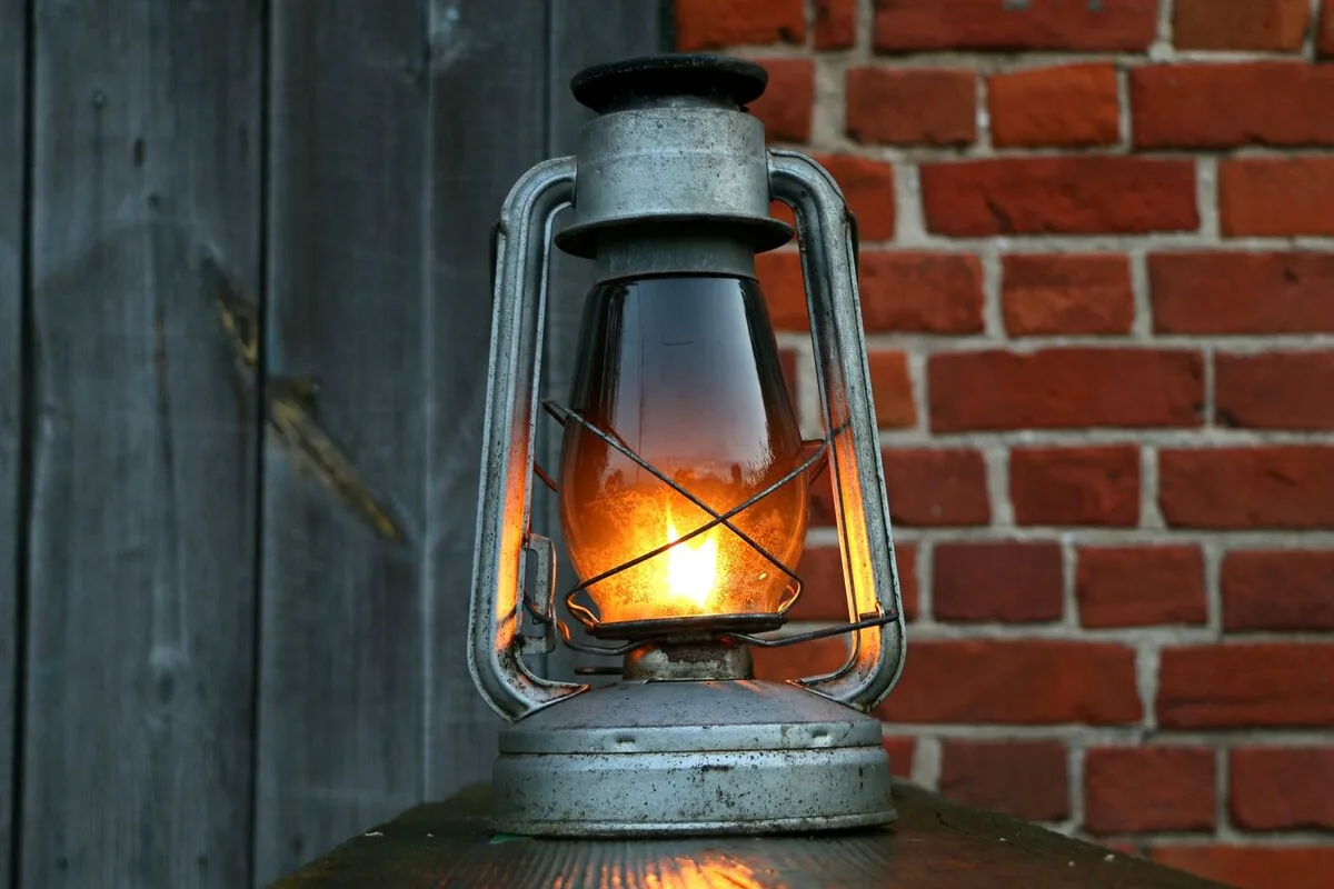 Zapalona lampa naftowa przy ceglanej ścianie