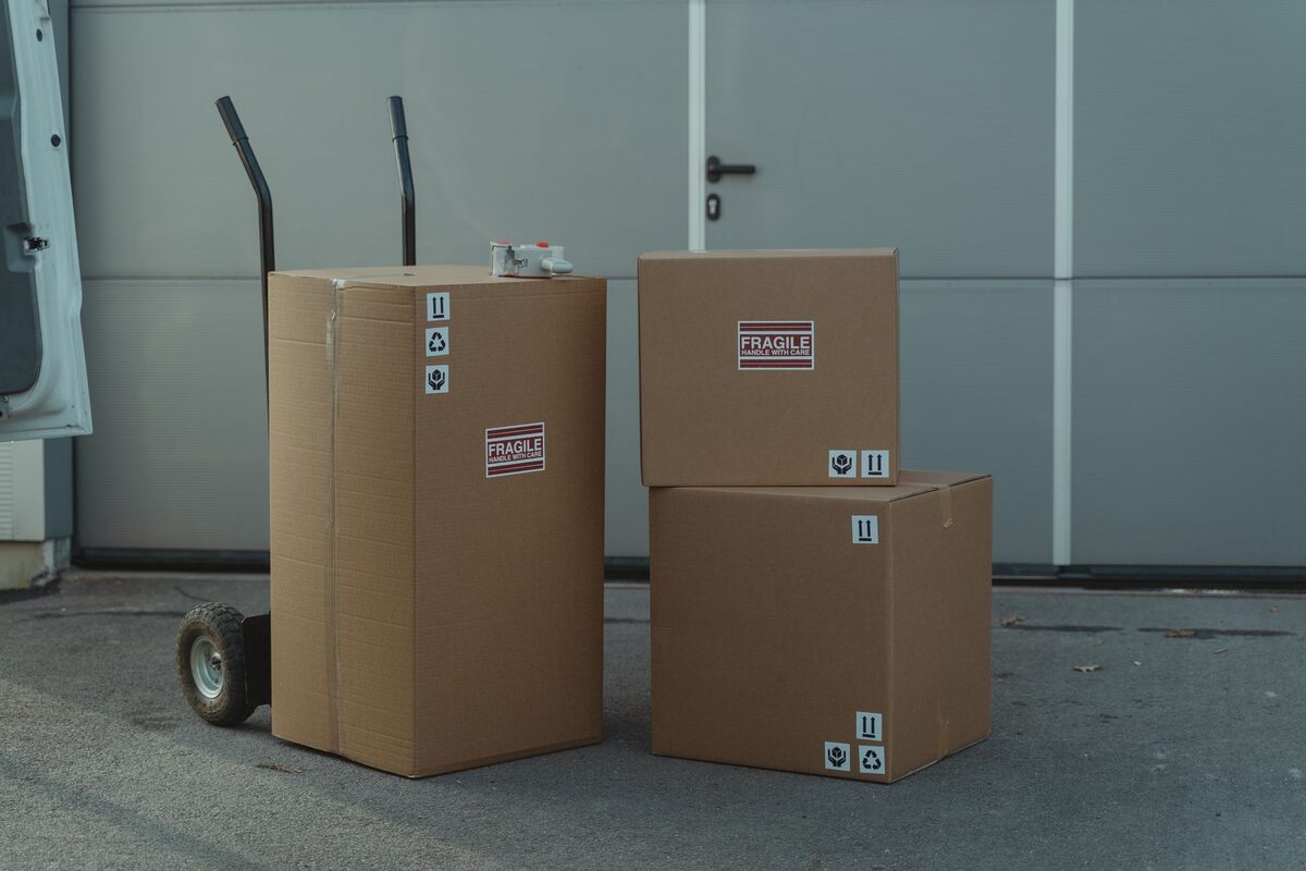 Kartony przygotowane do przyjęcia na magazyn obok wózka transportowego