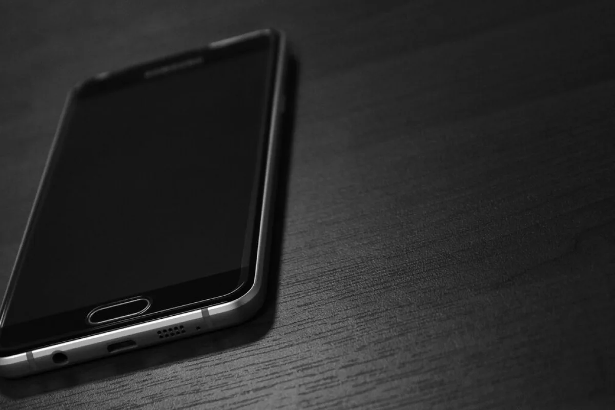 Telefon leżący ekranem do góry na ciemnym blacie