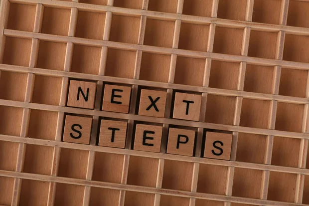Drewniane litery układające się w napis „next steps” — cztery kroki współpracy
